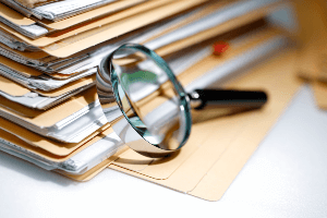 A magnifying glass resting on a stack of files