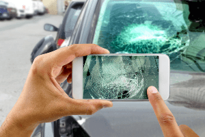 Picture of a person taking a photo of a cracked windshield 
