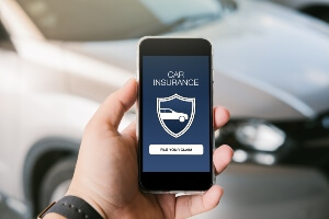 driver holding smartphone displaying insurance claim options