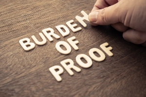 Someone spelling out the words burden of proof on a table. 