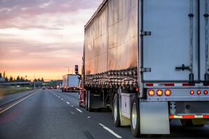 Twilight image of multiple semi-trucks on a highway.