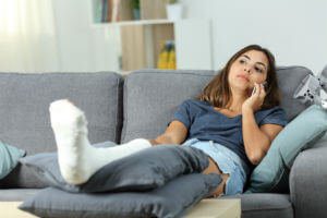 woman-on-couch-with-broken-leg-on-phone